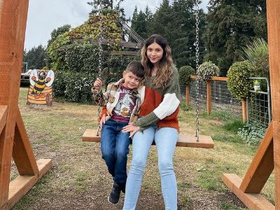 Both Brianna Jaramillo and Braeson are sitting in a swing.